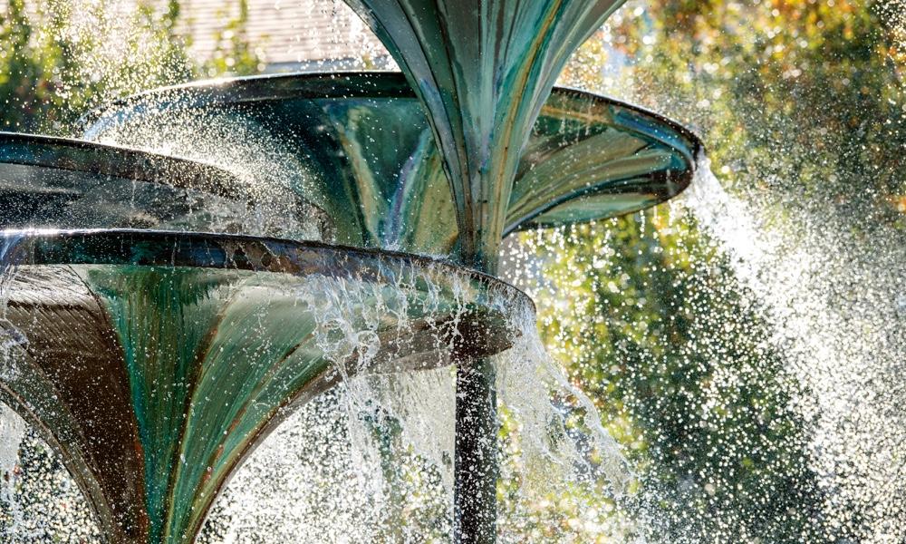 Close up view of water cascading from the trumpet-shaped forms of TCU landmark Frog Fountain
